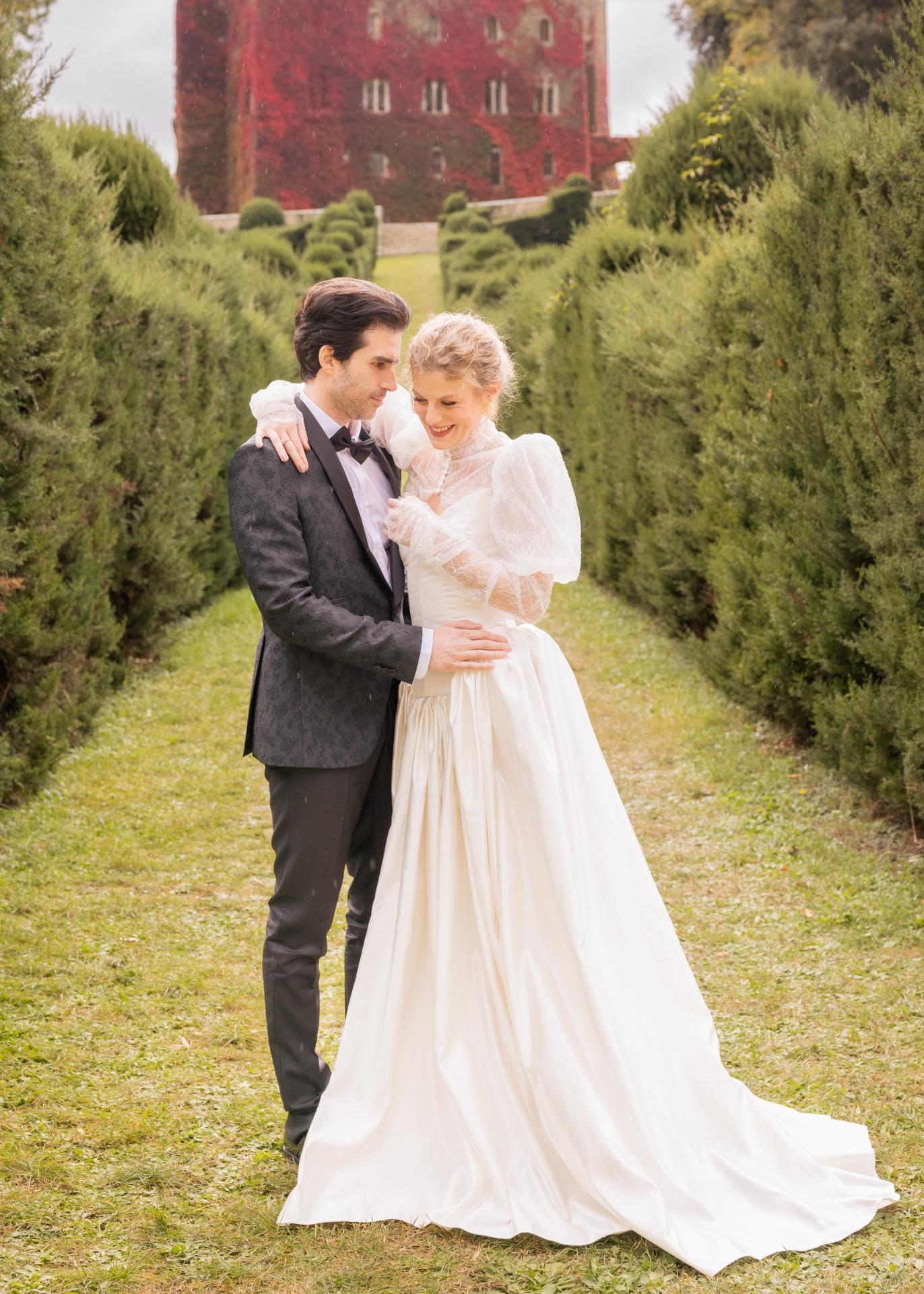 Bride and groom embracing in a manicured garden during an elegant luxury wedding at Castello di Celsa in Tuscany.