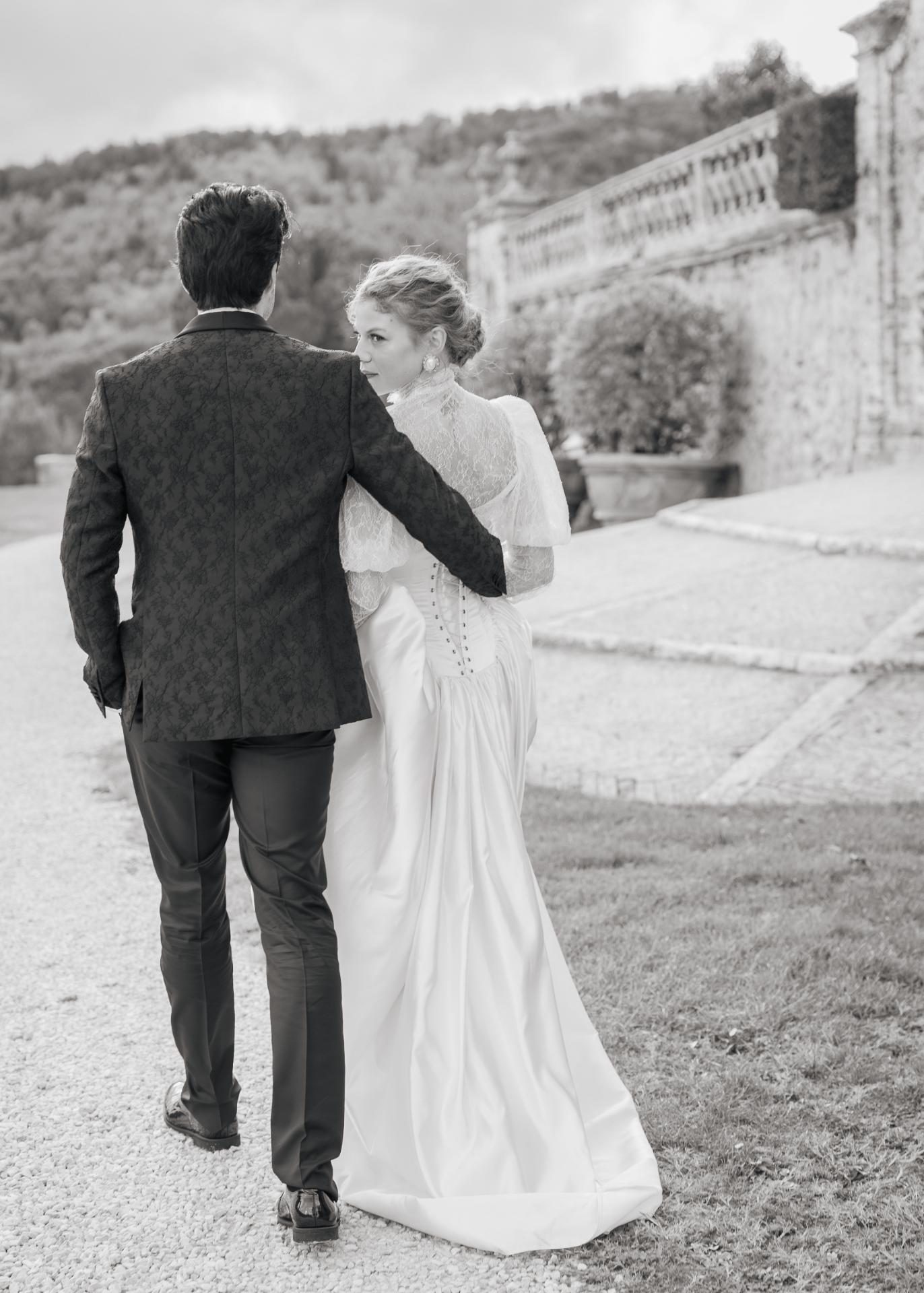 Black and white wedding photo of bride and groom walking together at Castello di Celsa in Tuscany.