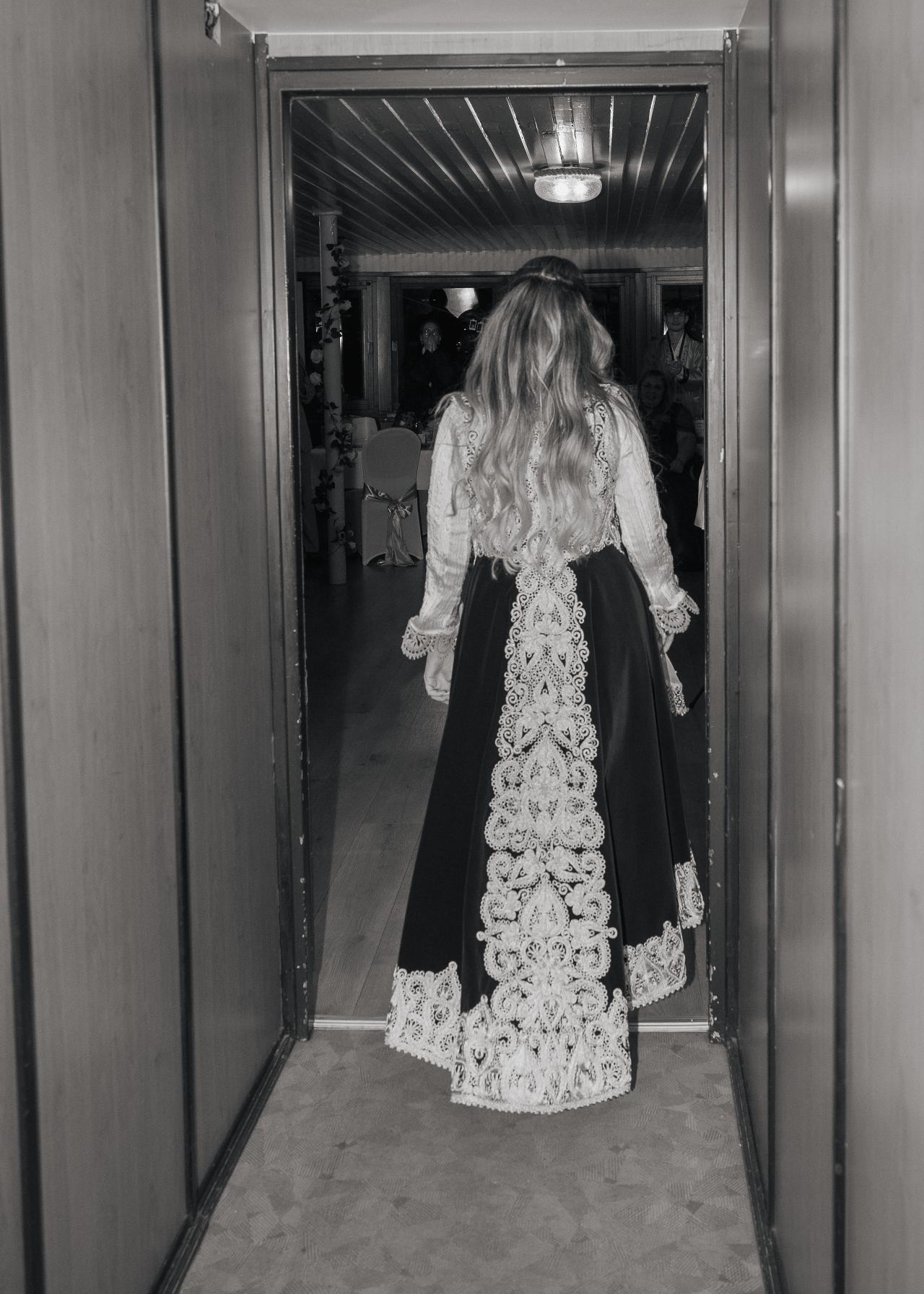 Bride walking into the wedding reception wearing an elegant traditional dress, photographed from behind