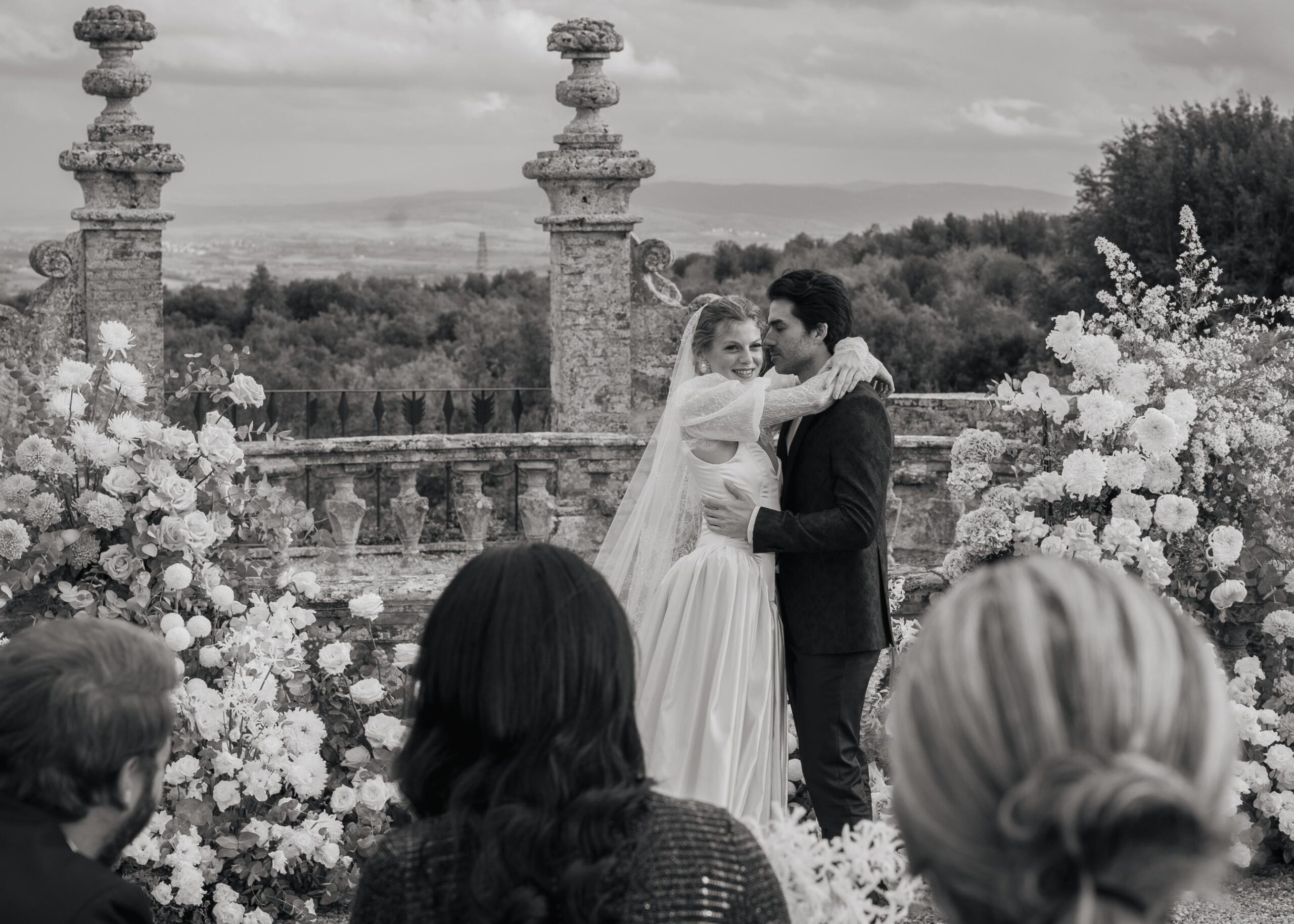 Black and white wedding ceremony at Castello di Celsa with bride and groom embracing in front of an elegant floral altar in Tuscany