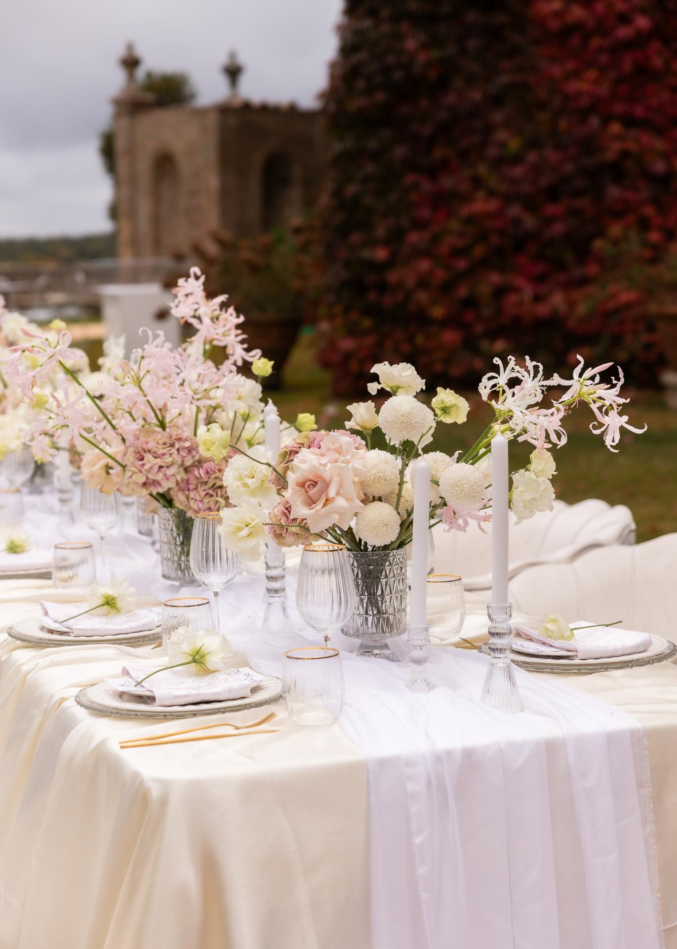 Elegant wedding table setting with pastel florals, candles, and fine glassware at an Italian villa outdoor reception.