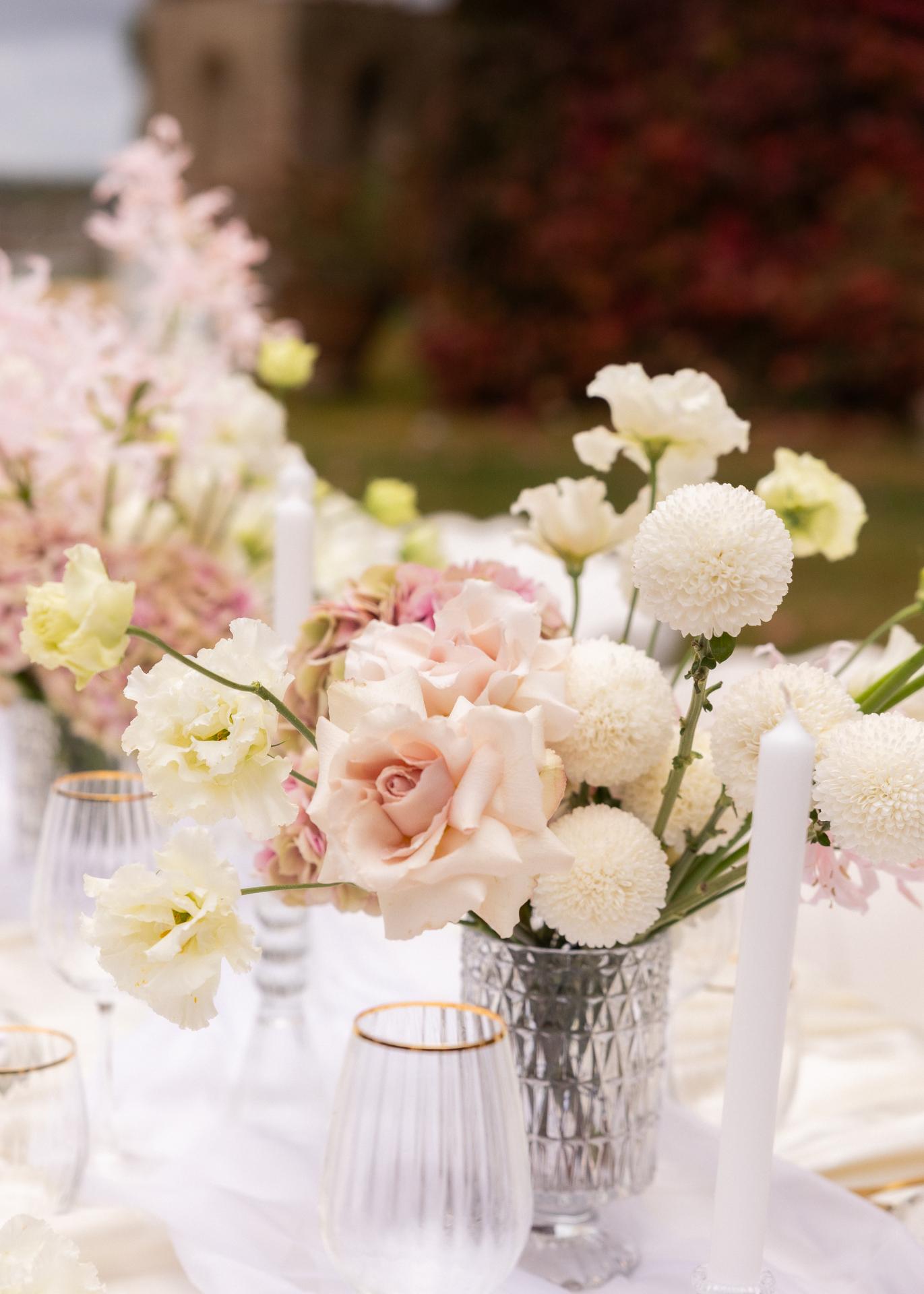 Elegant wedding table setting with pastel florals, candles, and fine glassware at an Italian villa outdoor reception.