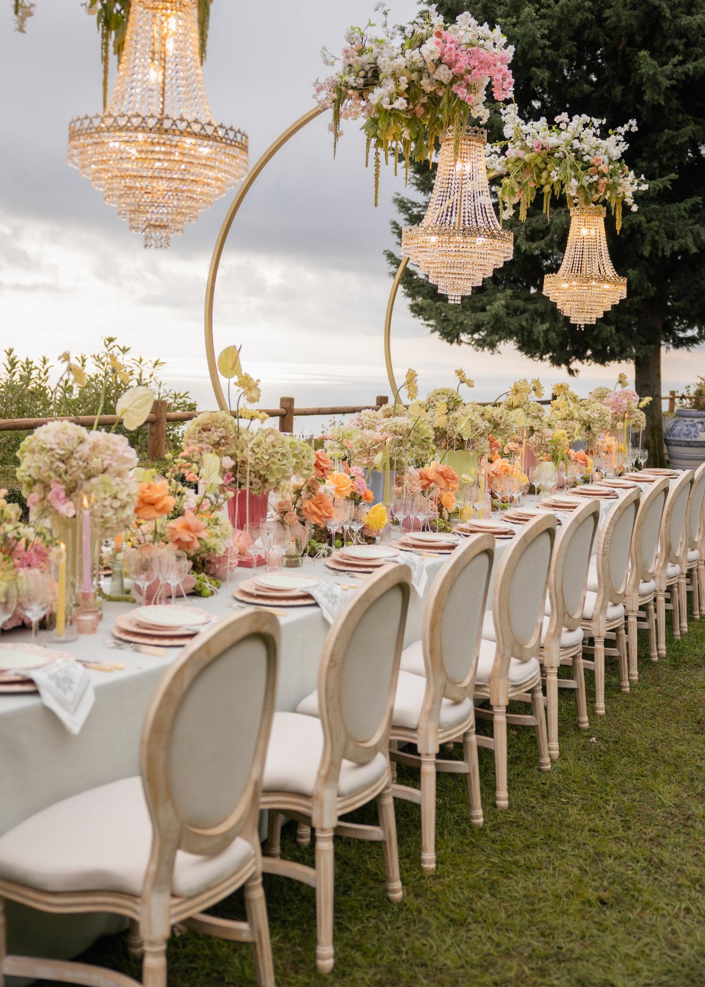 Elegant outdoor wedding reception table with pastel florals, crystal chandeliers, and refined place settings at a luxury Italian wedding.