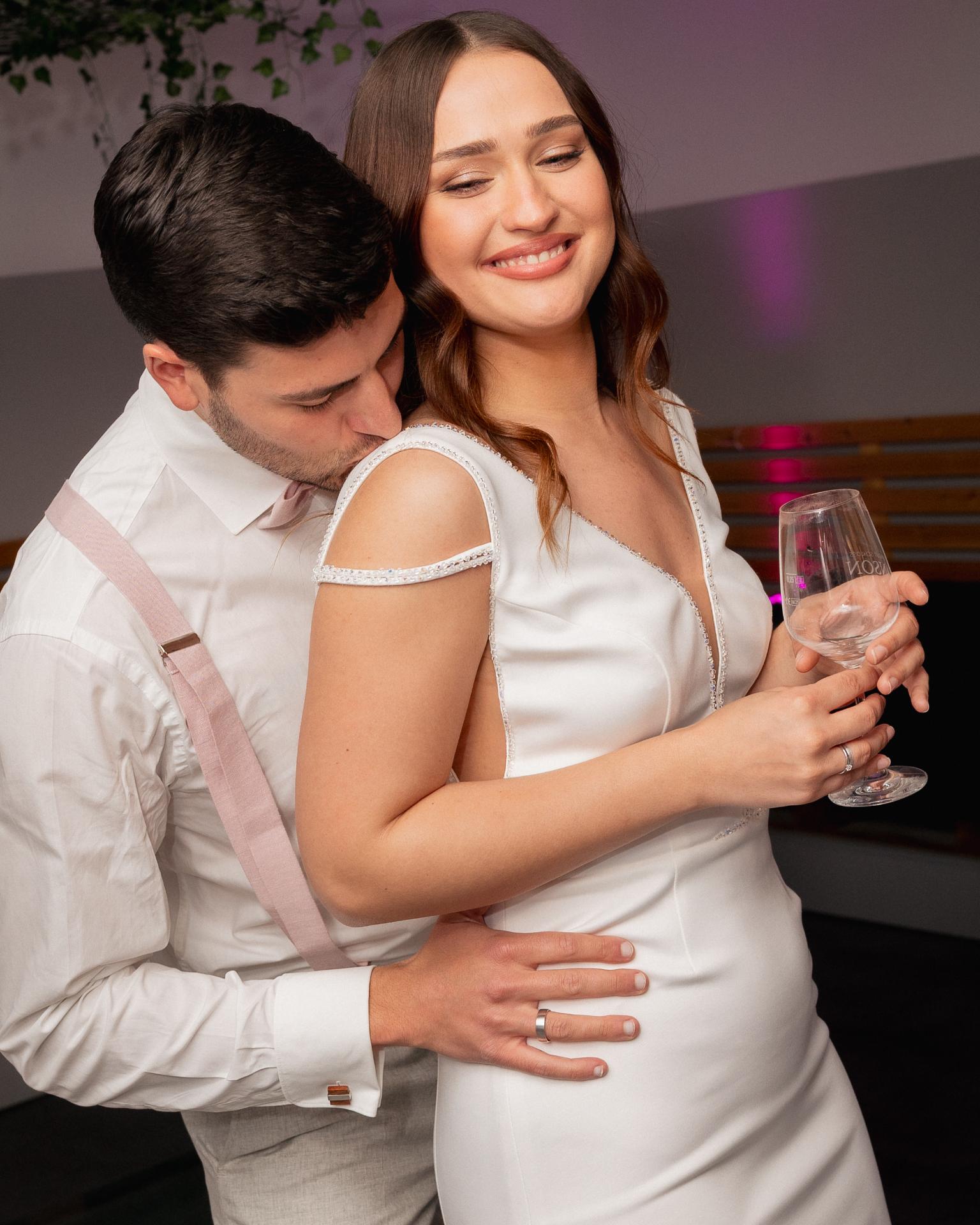 Bride and groom dancing closely during the wedding after party, holding a champagne glass