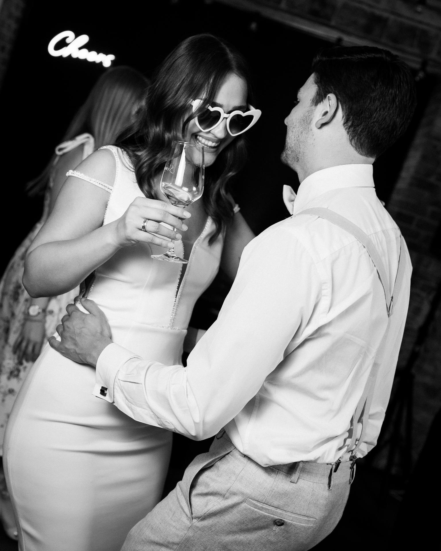 Bride and groom dancing together during the wedding party, captured in a candid black and white moment