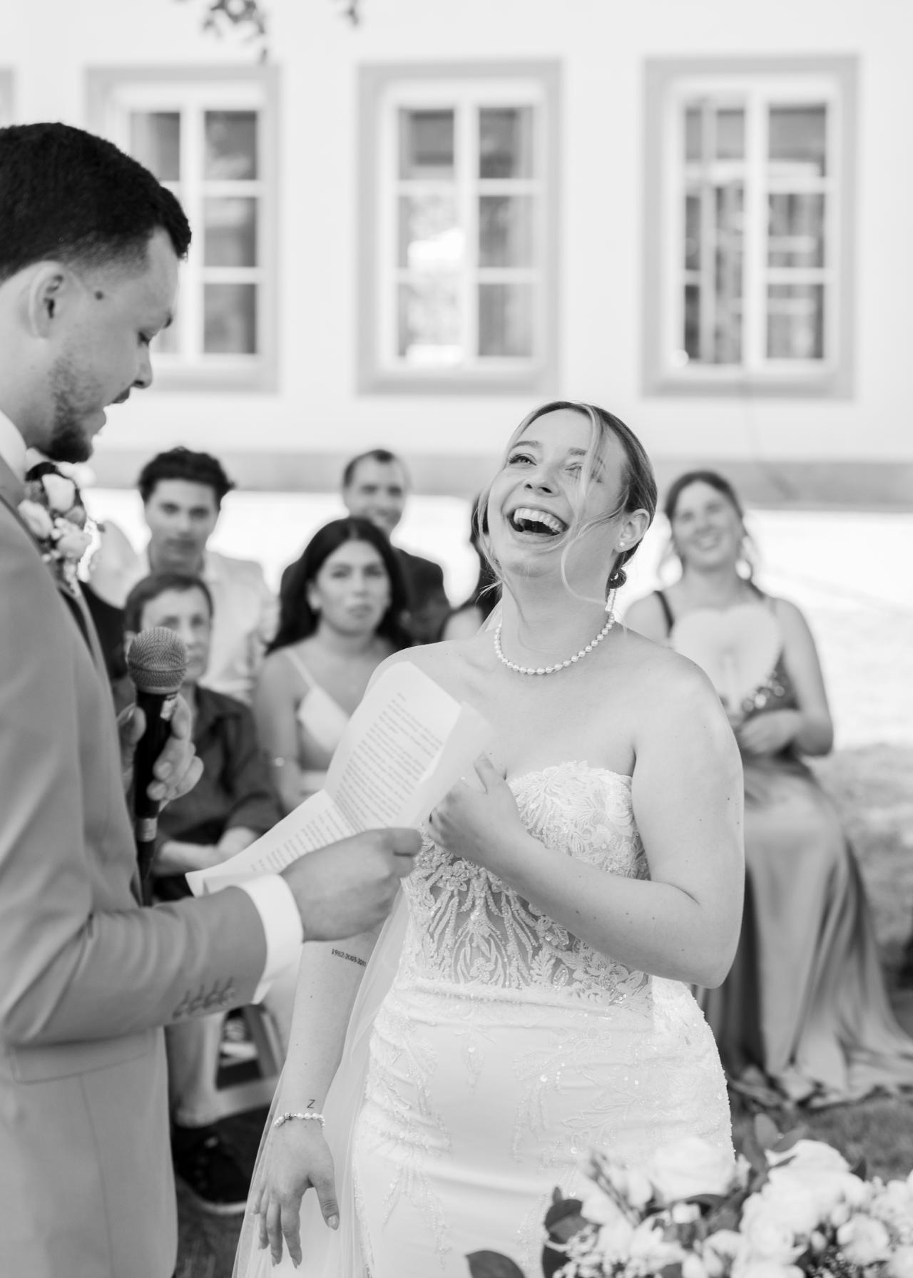 Bride laughing during the wedding vows while the groom reads from his notes