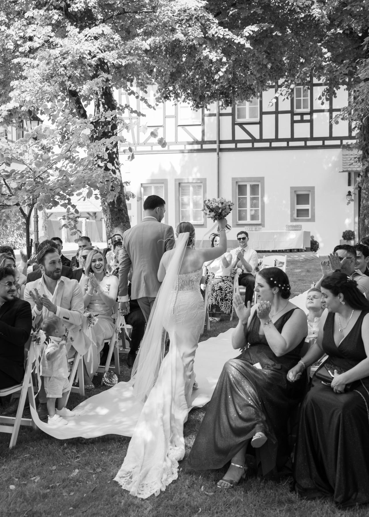 Bride and groom walking down the aisle after the ceremony, guests applauding during an outdoor wedding