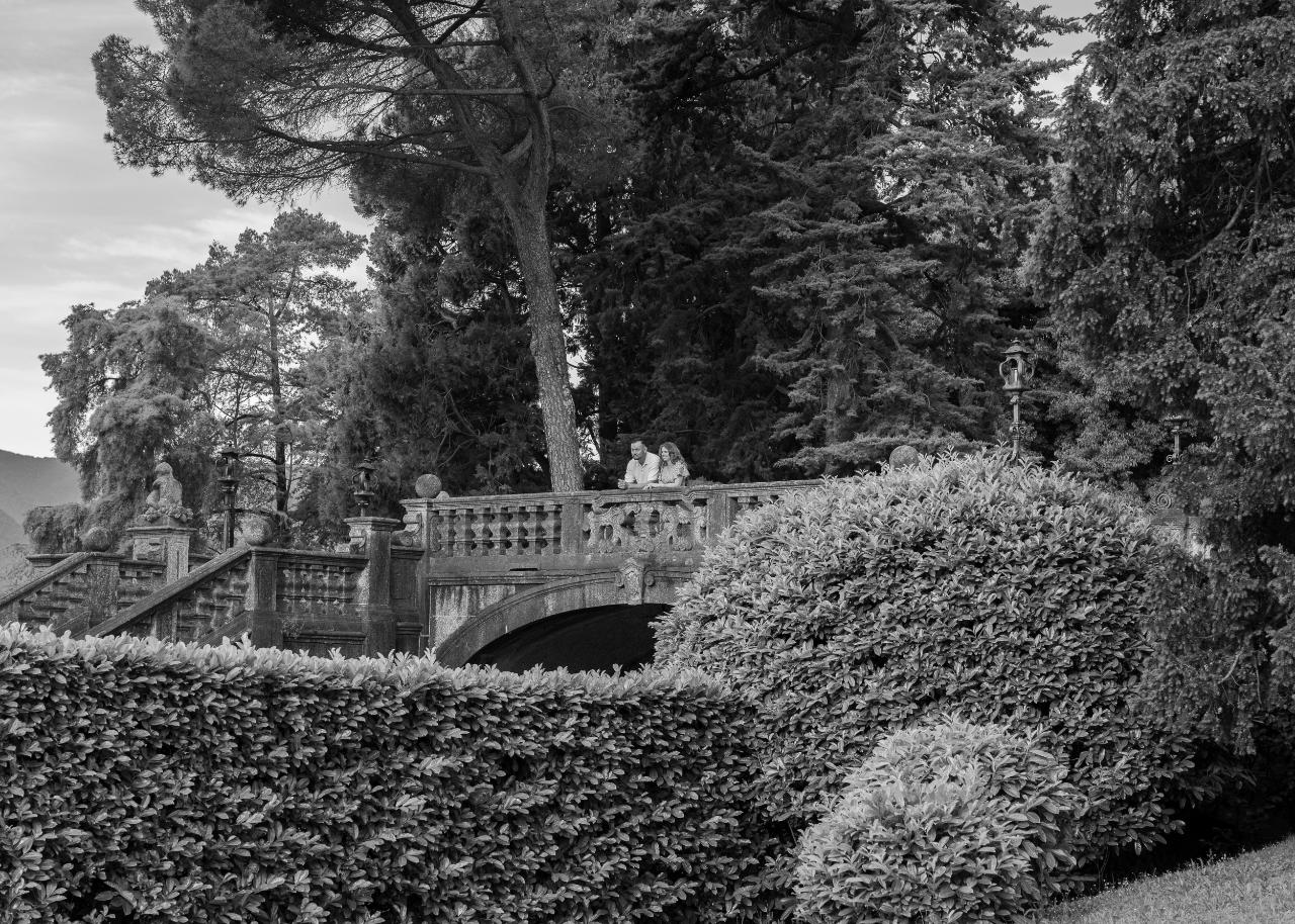 Engaged couple standing on a stone bridge in a Lake Como villa garden