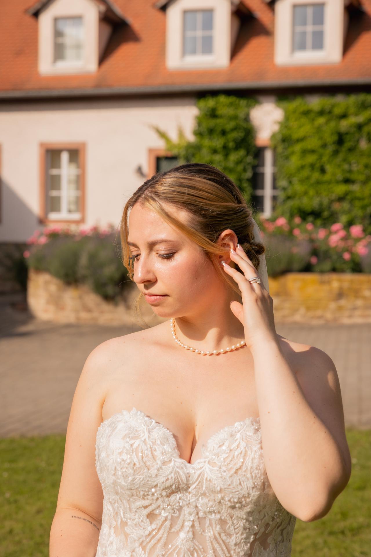 Elegant bridal portrait in natural light wearing a lace wedding dress and pearl necklace