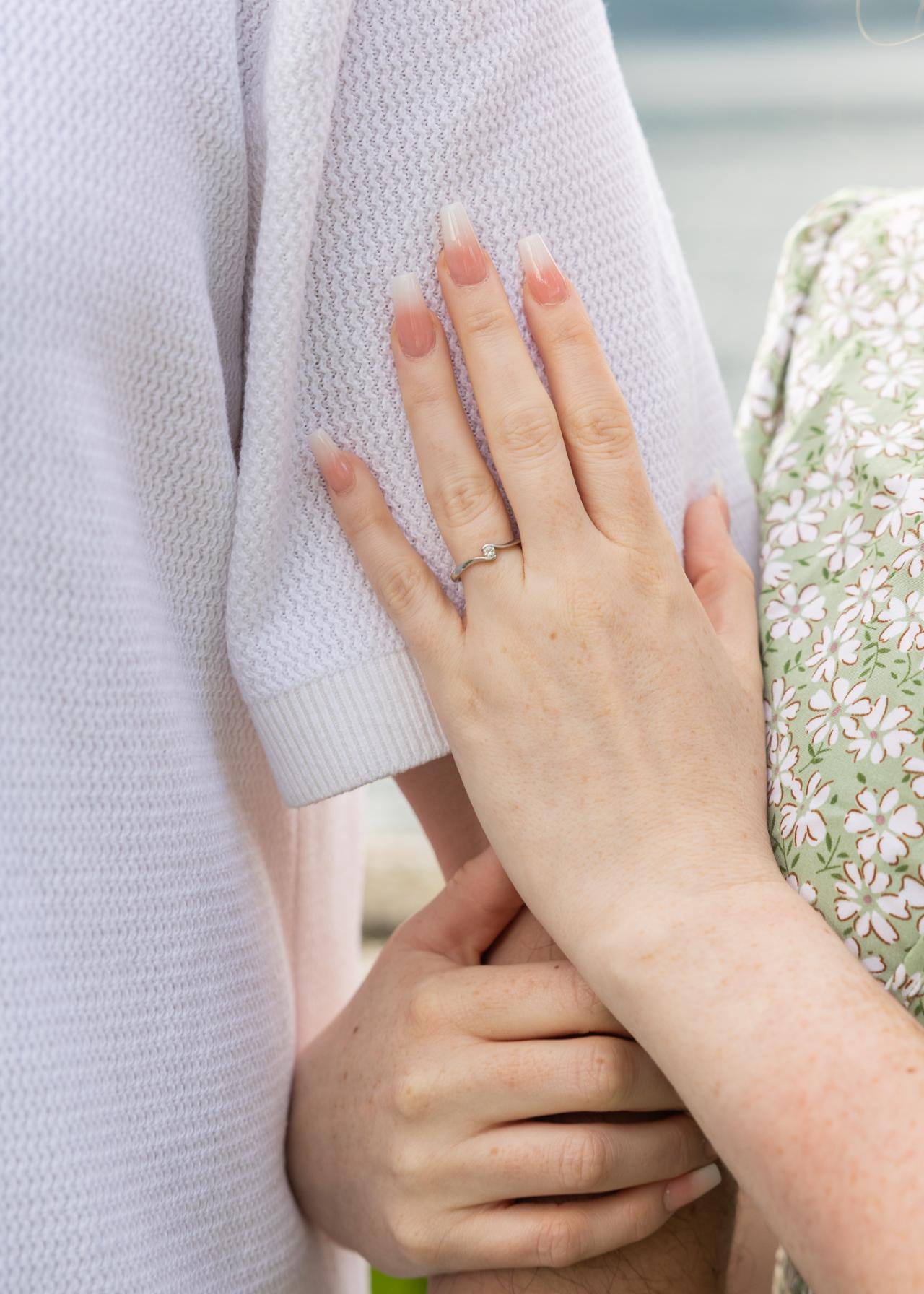 Close-up of an engagement ring on a couple’s hands