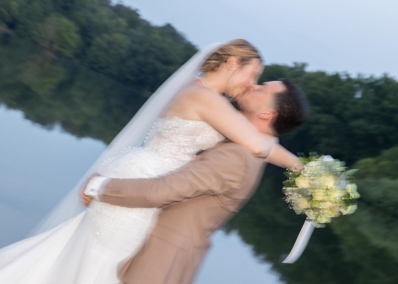 Bride and groom kissing by the lake during an emotional wedding portrait with motion blur