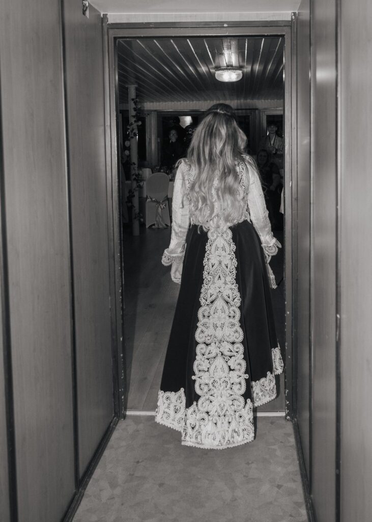 Bride walking into the wedding reception wearing an elegant traditional dress, photographed from behind