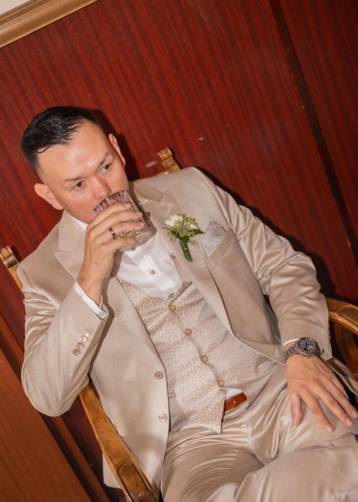 Groom in a light wedding suit enjoying a quiet moment indoors