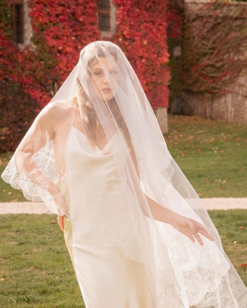 Modern bride in a minimalist silk wedding dress with pearl necklace at Castello di Celsa, Tuscany, captured in soft autumn light.