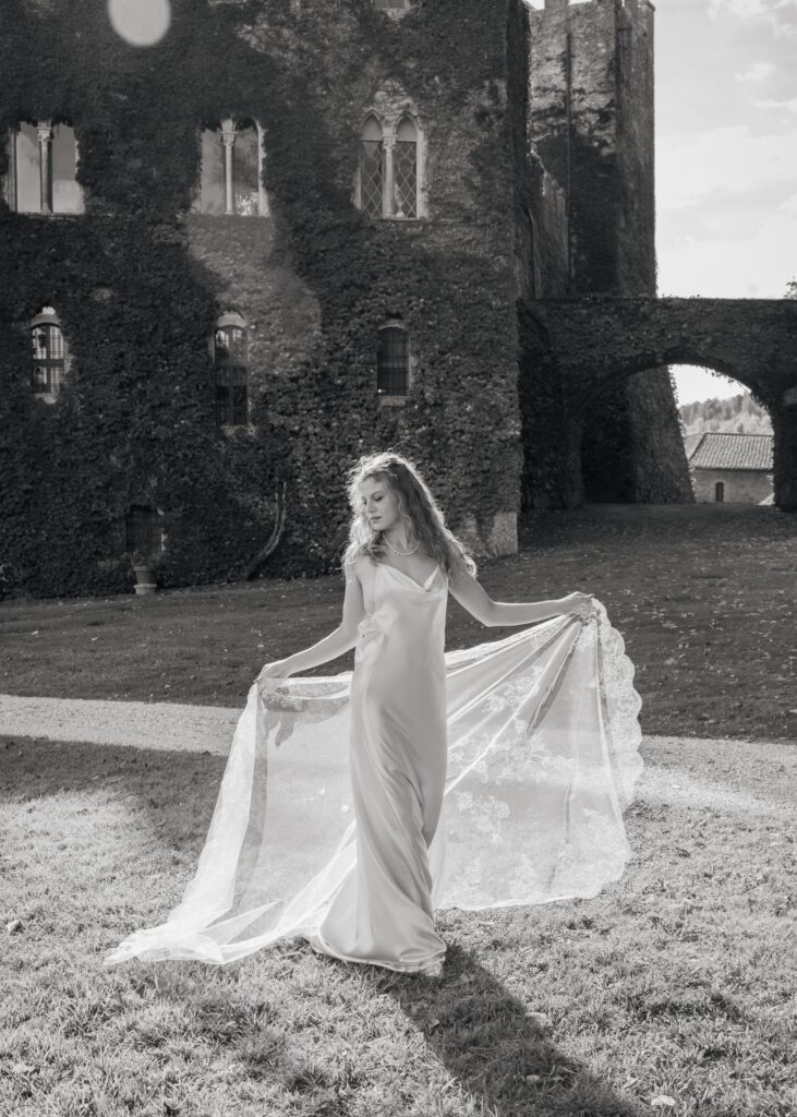 Modern bride in a minimalist silk wedding dress with pearl necklace at Castello di Celsa, Tuscany, captured in soft autumn light.