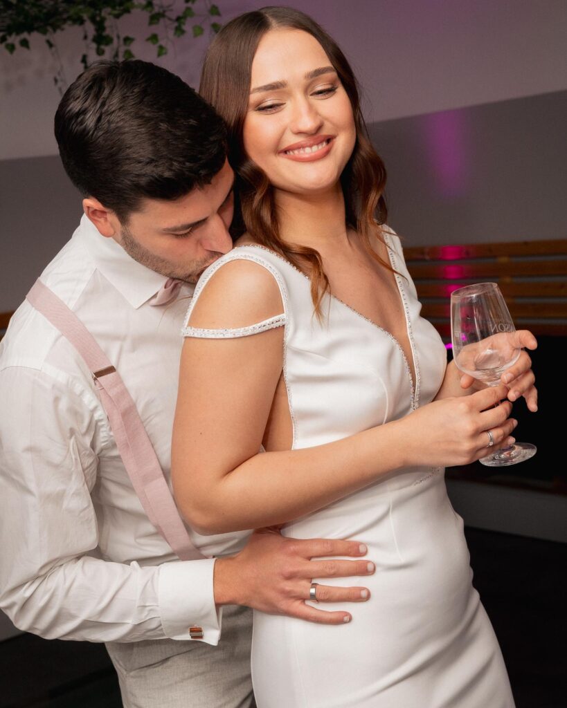 Bride and groom dancing closely during the wedding after party, holding a champagne glass