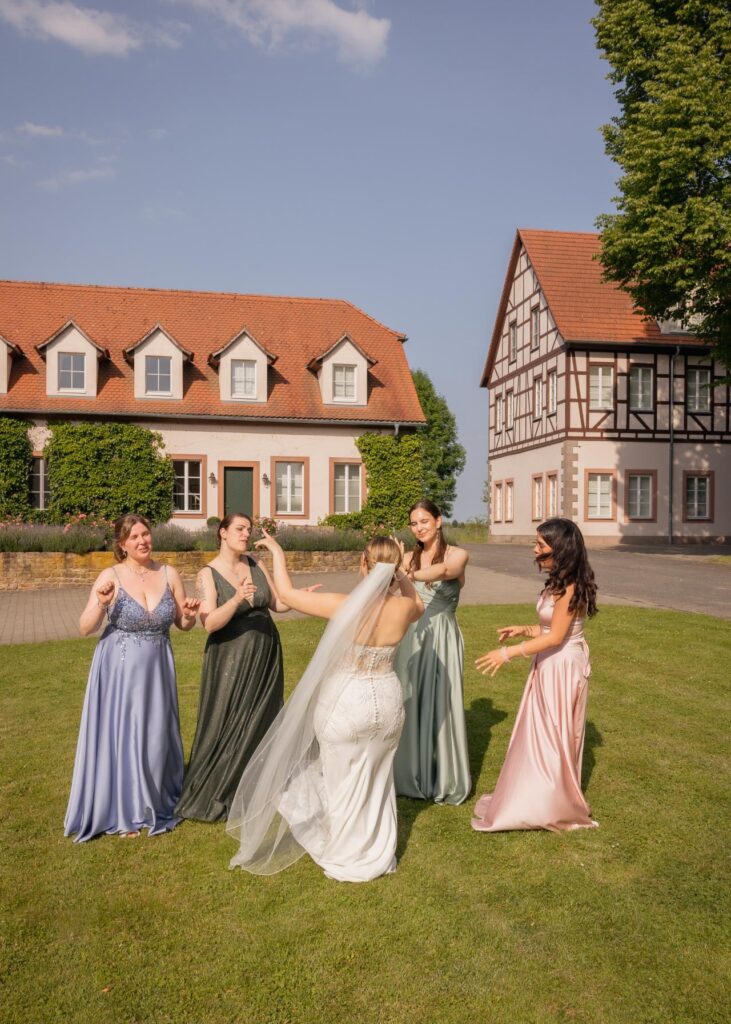 Bride celebrating with bridesmaids in pastel dresses in the garden of an elegant wedding estate